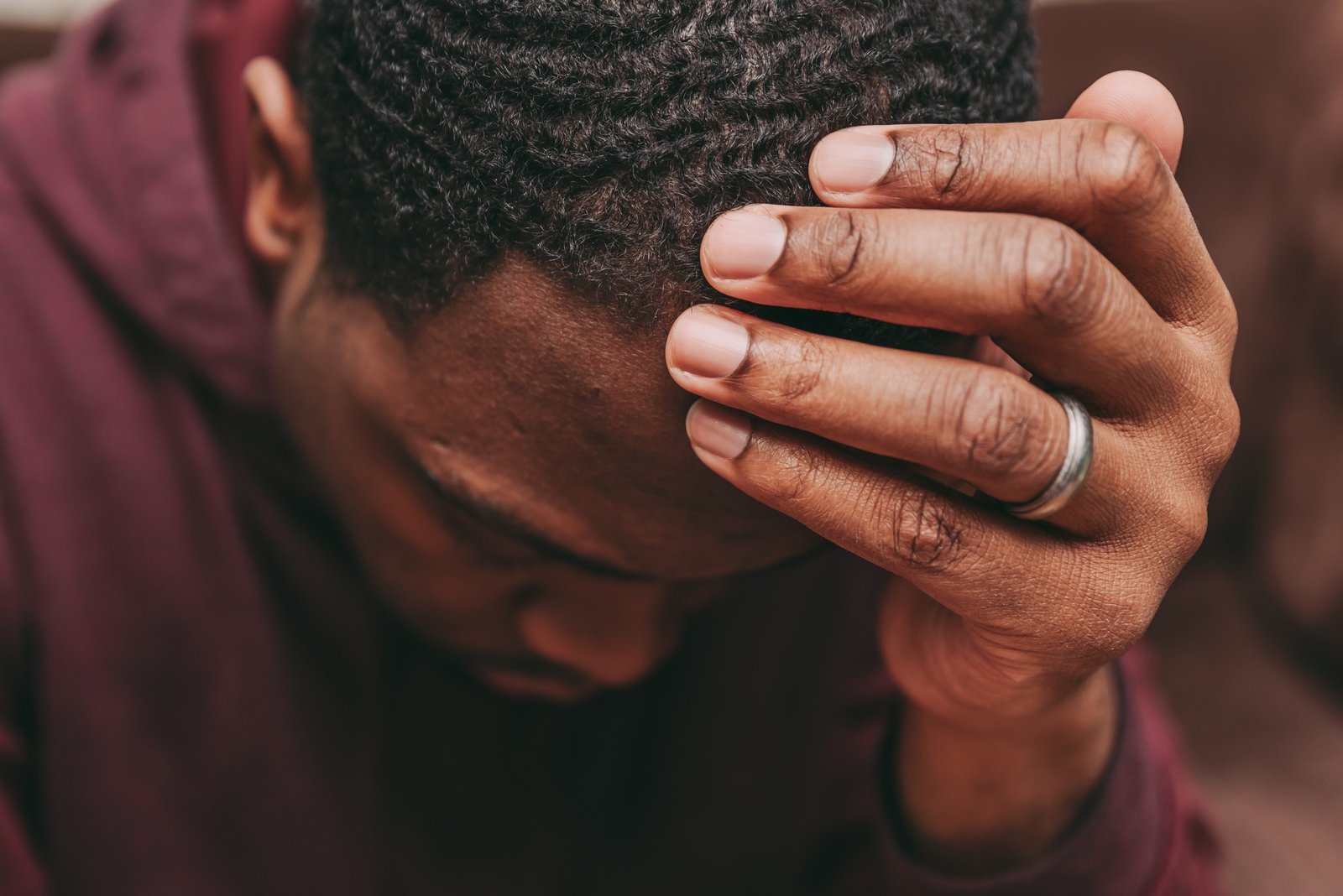 African American man with head in hand looking down and depressed